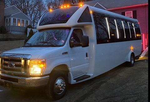 A white shuttle bus is parked in front of a house.