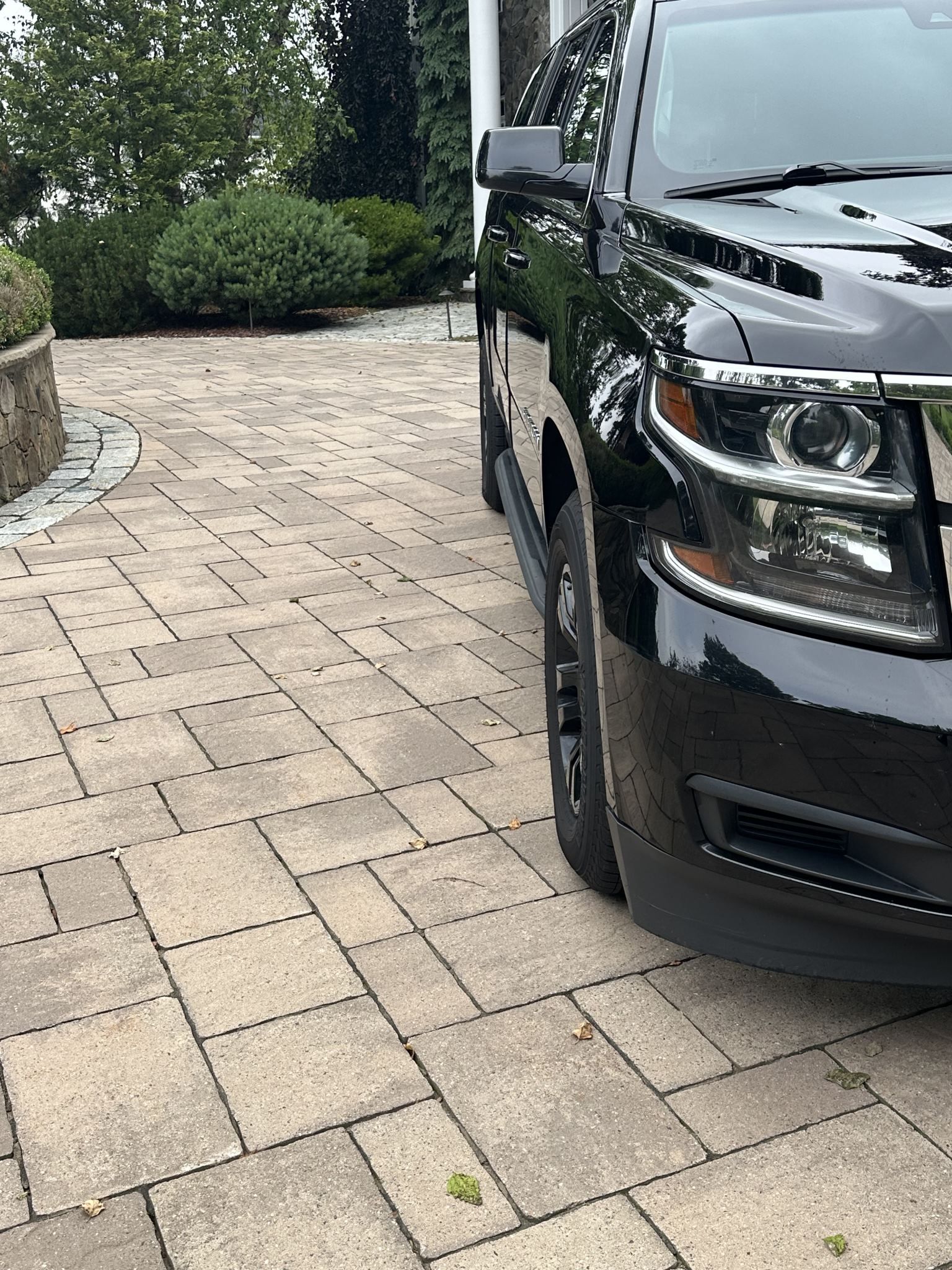 A black suv is parked on a brick driveway.