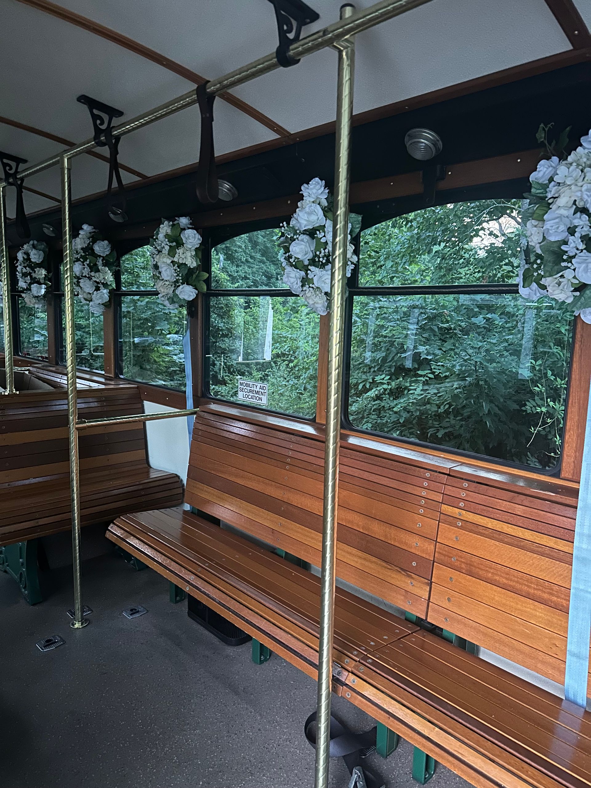 The inside of a bus with wooden benches and flowers on the windows