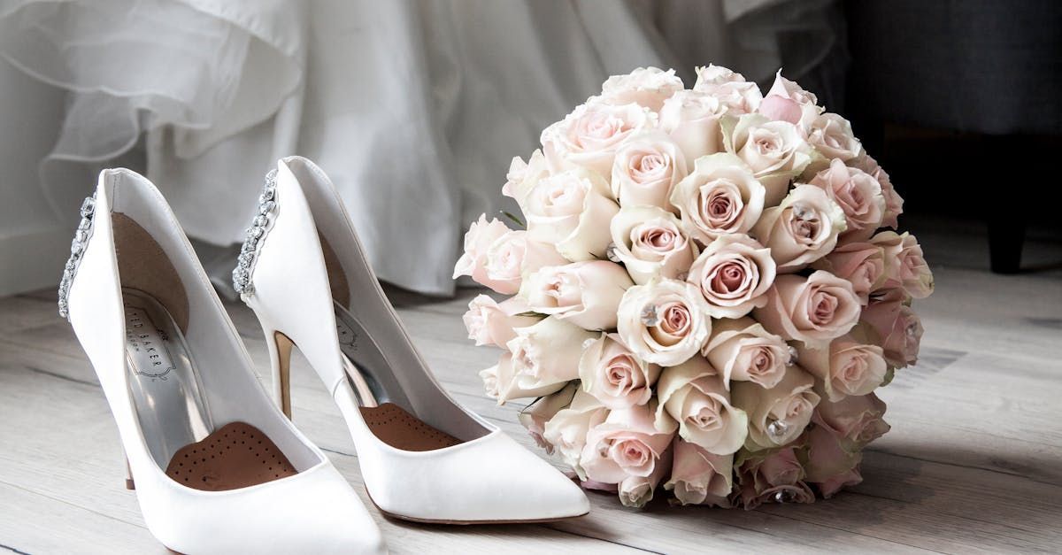 A bouquet of roses is sitting next to a pair of wedding shoes.