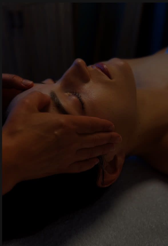 A woman is getting a head massage with her eyes closed