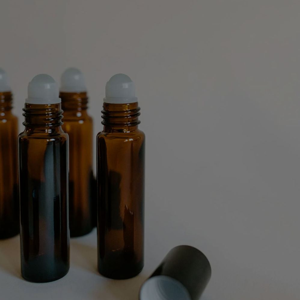 A group of brown bottles with white caps are lined up on a table.