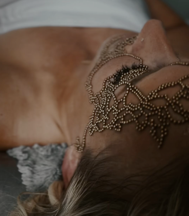 A woman wearing a headpiece is laying down on a bed.