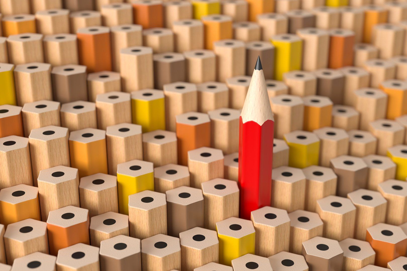 Ein roter Bleistift sticht aus einem Stapel Bleistifte hervor.