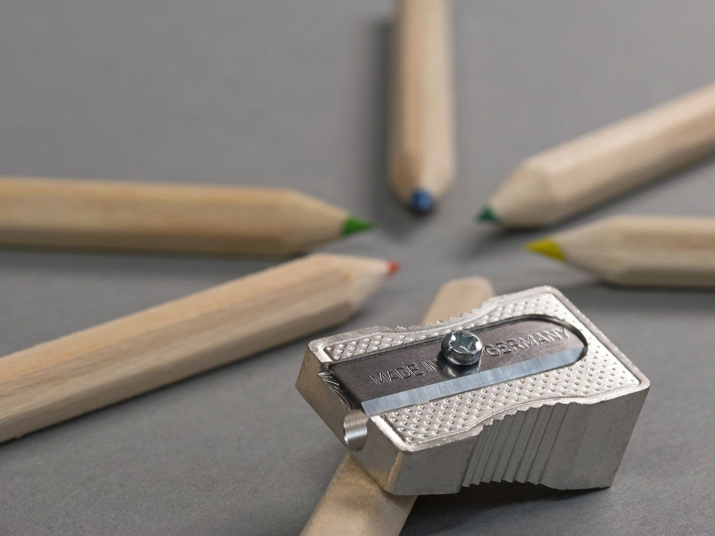 Ein Bleistiftspitzer aus Metall, umgeben von Holzstiften