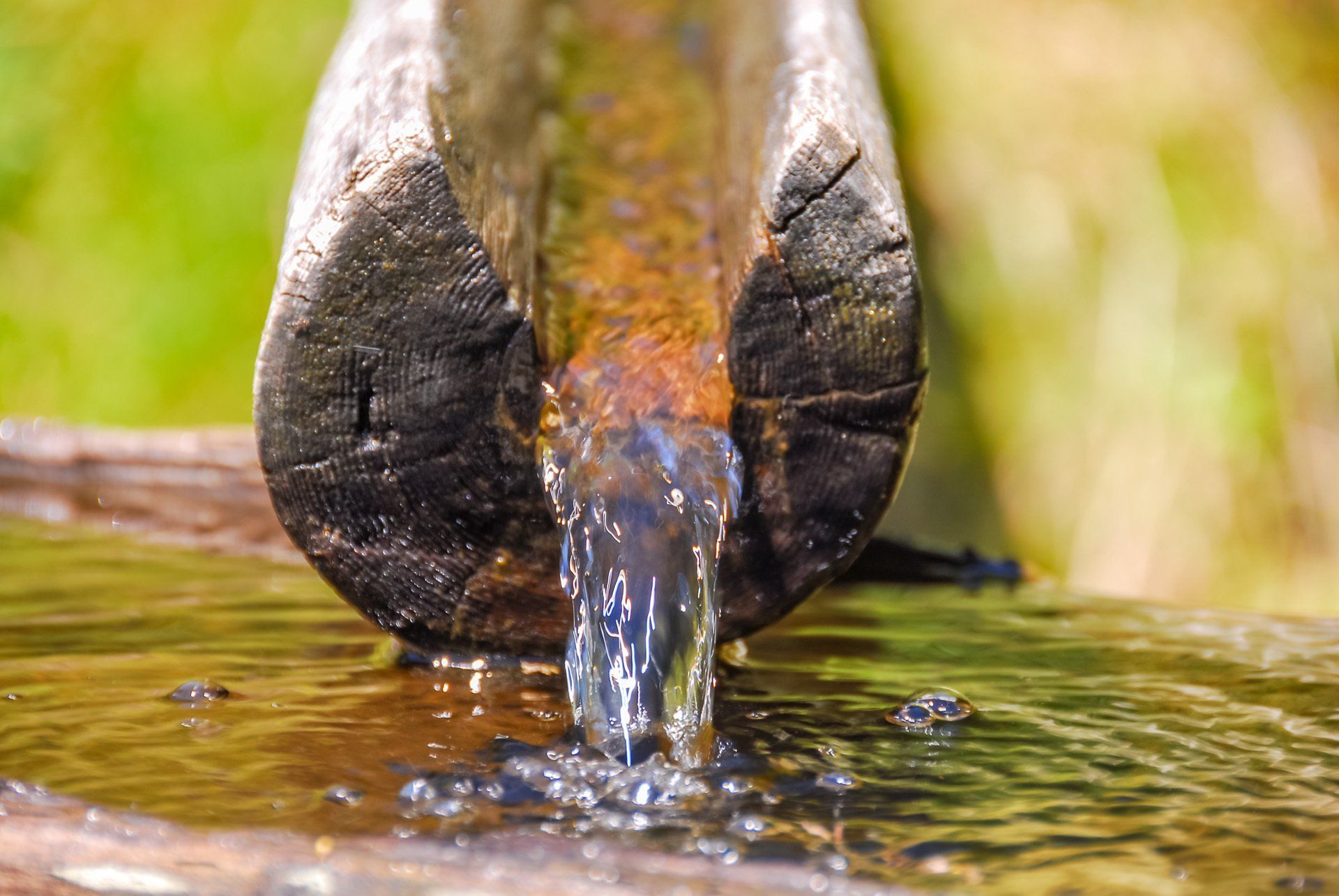 Eine Nahaufnahme eines Holzrohrs, aus dem Wasser kommt.