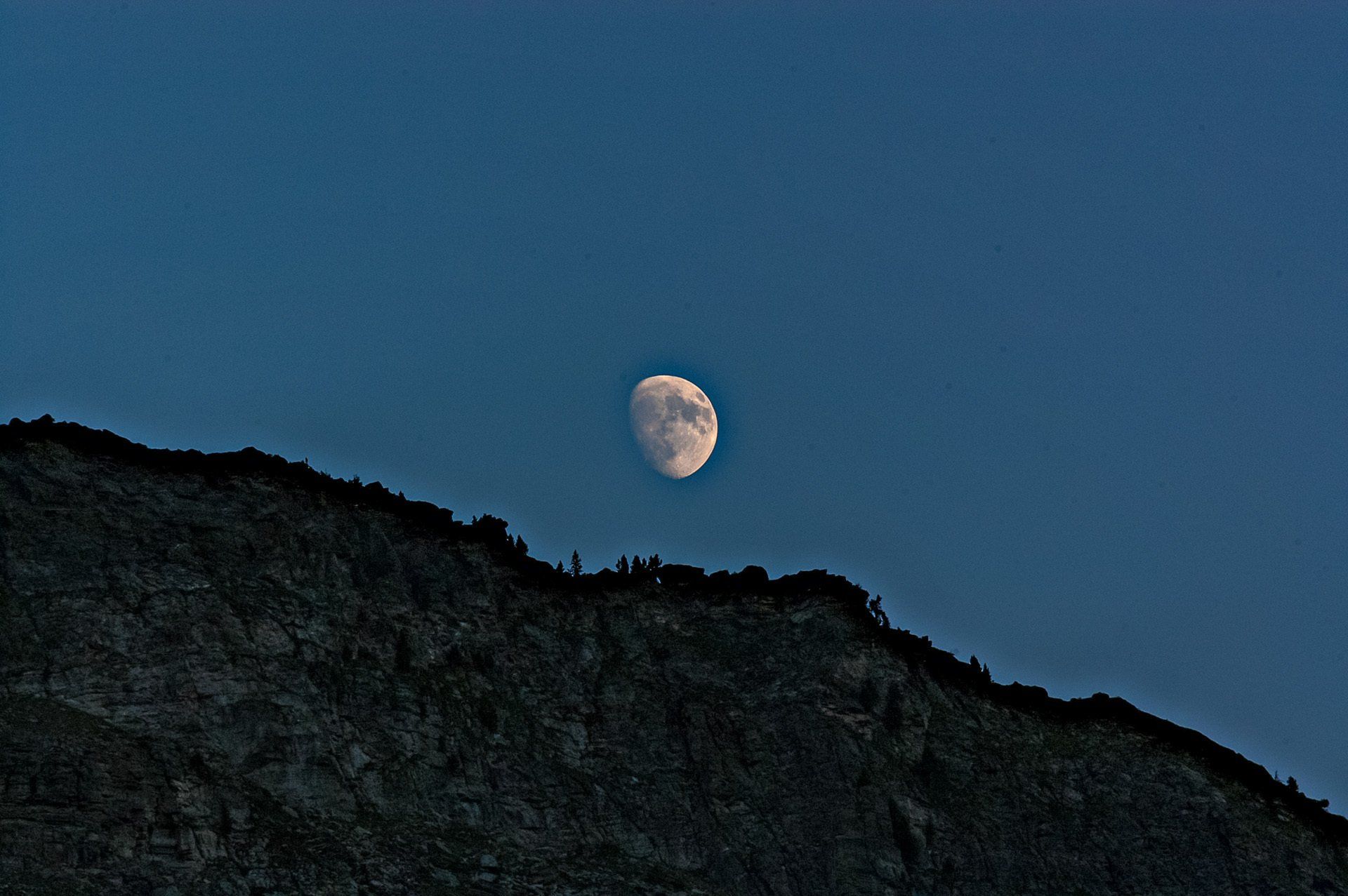 Ein Vollmond geht über einem dunklen Berg auf