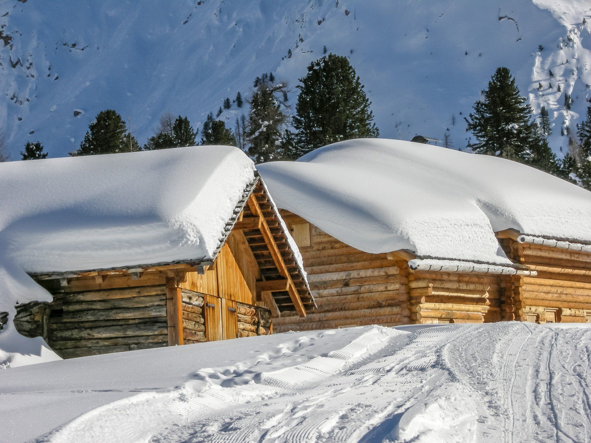 Zwei schneebedeckte Blockhütten mit Bäumen im Hintergrund