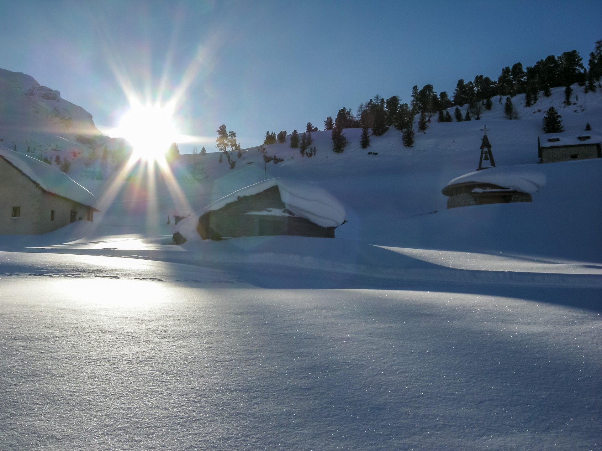 Die Sonne scheint hell auf eine verschneite Landschaft