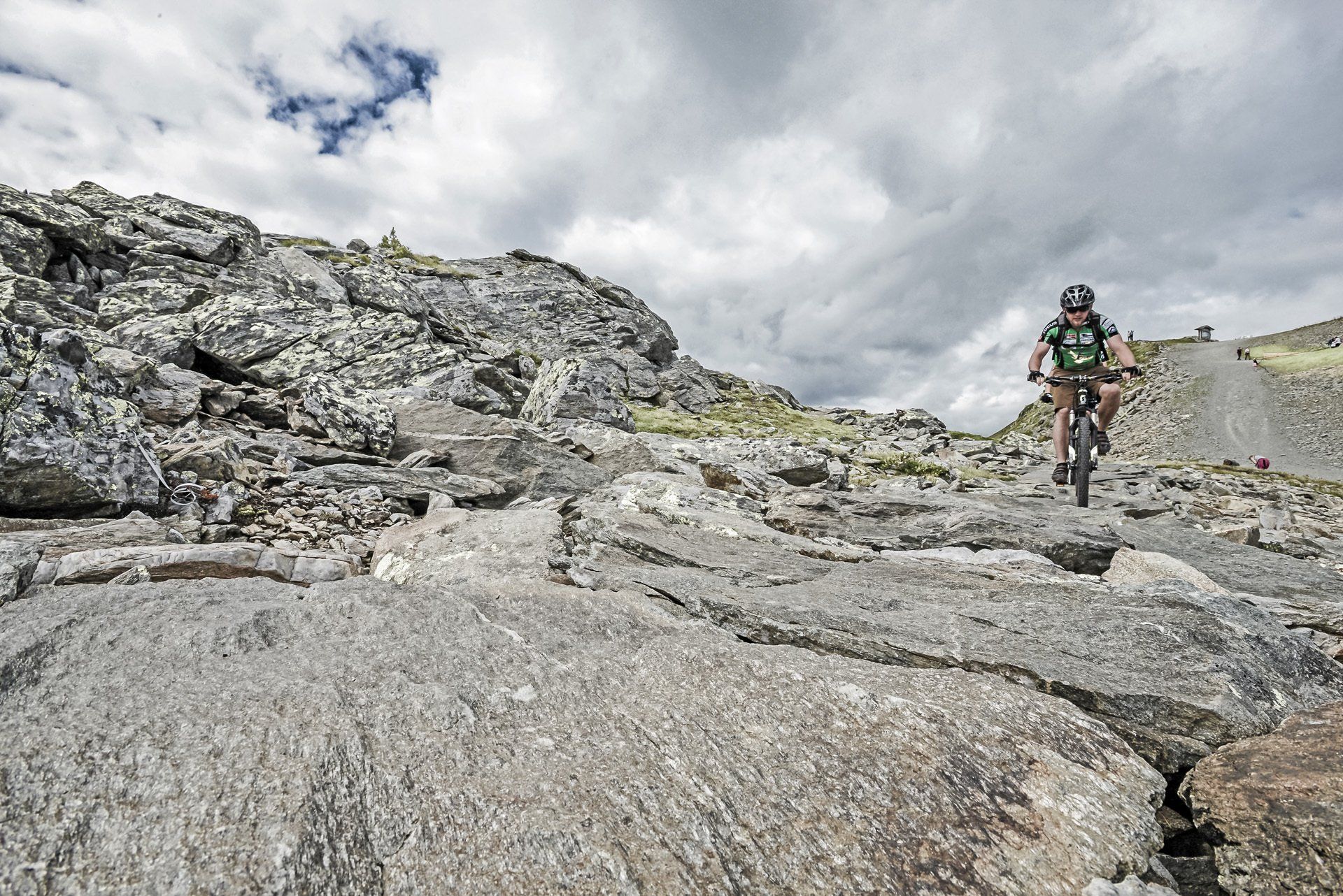 Eine Person fährt mit dem Fahrrad auf einer steinigen Straße.