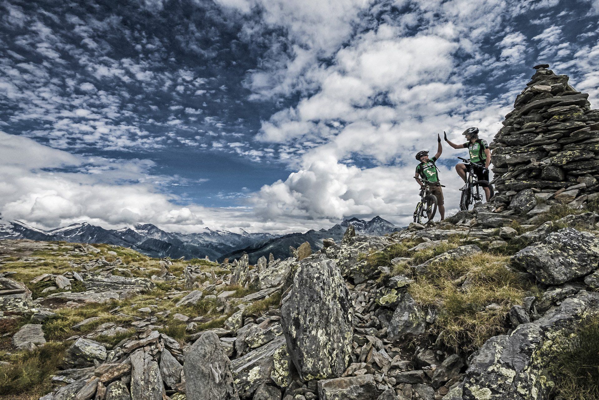 Zwei Leute stehen auf einem Berggipfel und geben sich gegenseitig ein High Five.