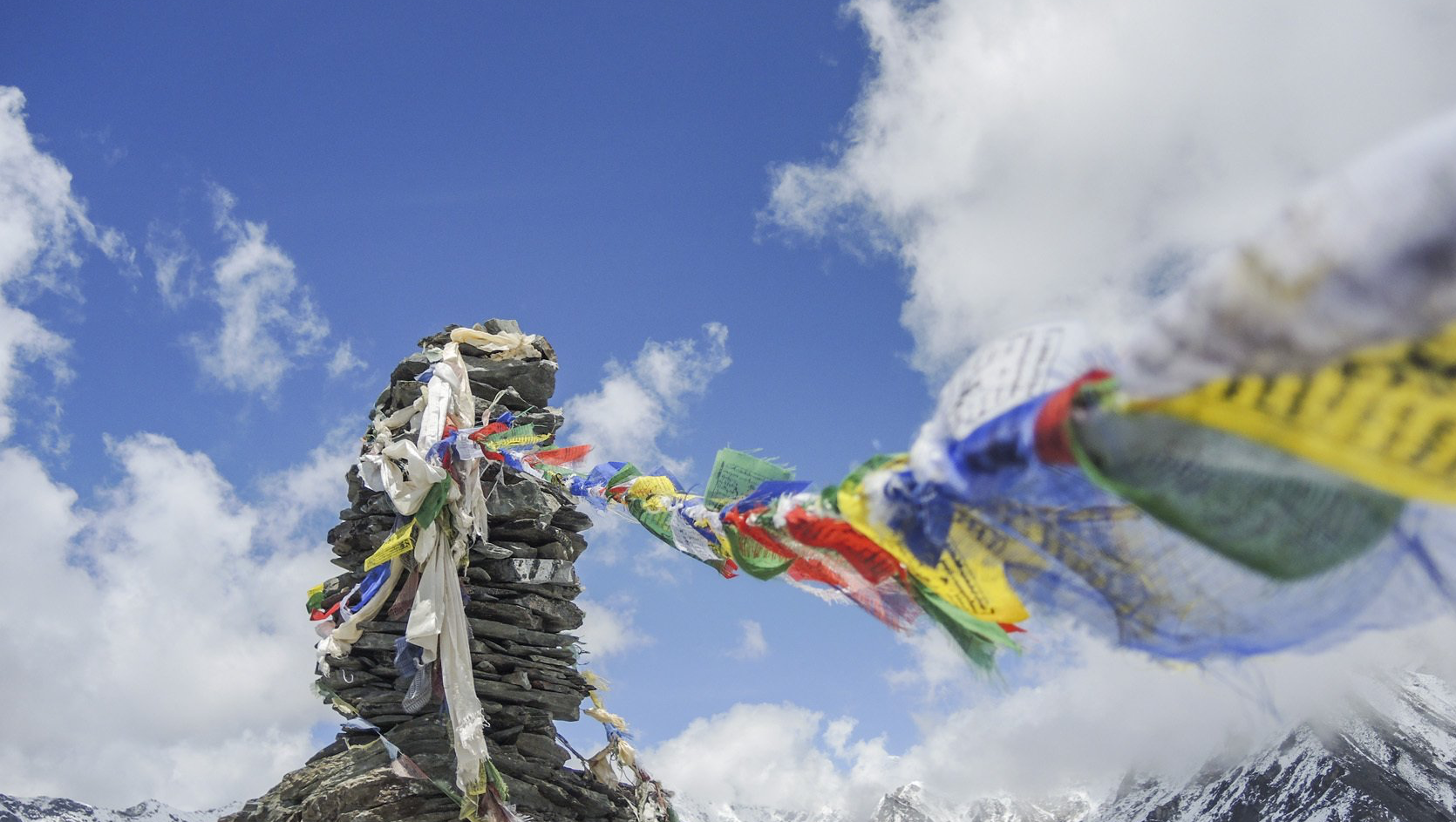 Auf einem Berggipfel wehen mehrere Flaggen im Wind.