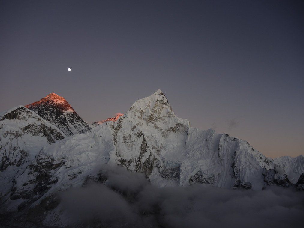 Ein schneebedeckter Berg mit einem Mond am Himmel