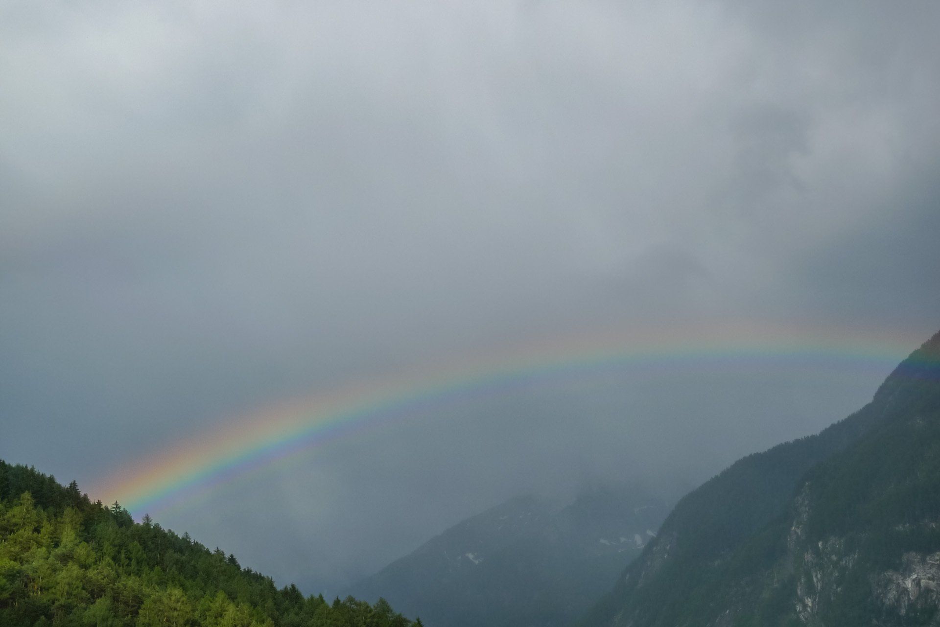 Über den Bergen ist ein Regenbogen am Himmel.