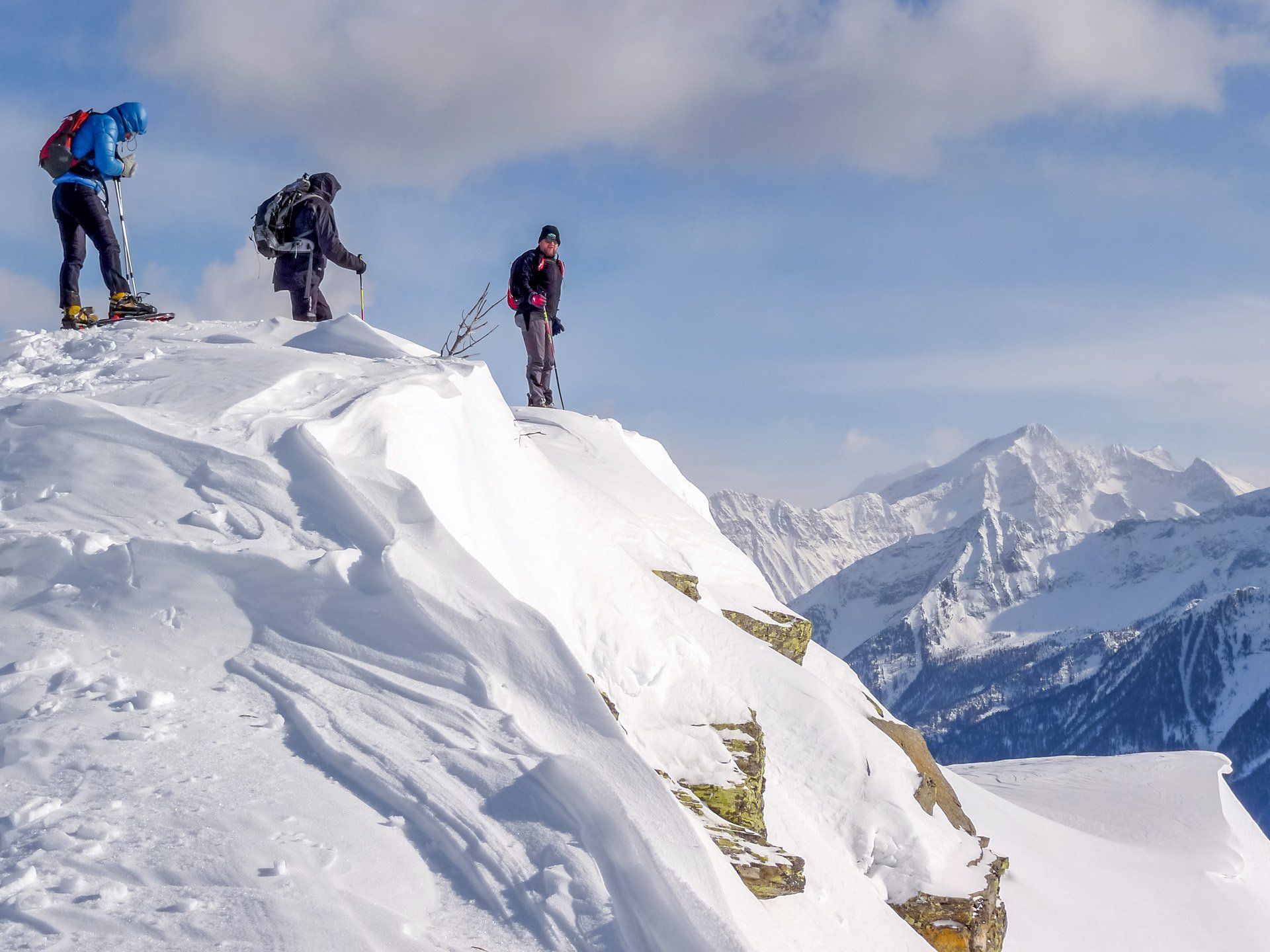 Drei Personen stehen auf einem schneebedeckten Berggipfel