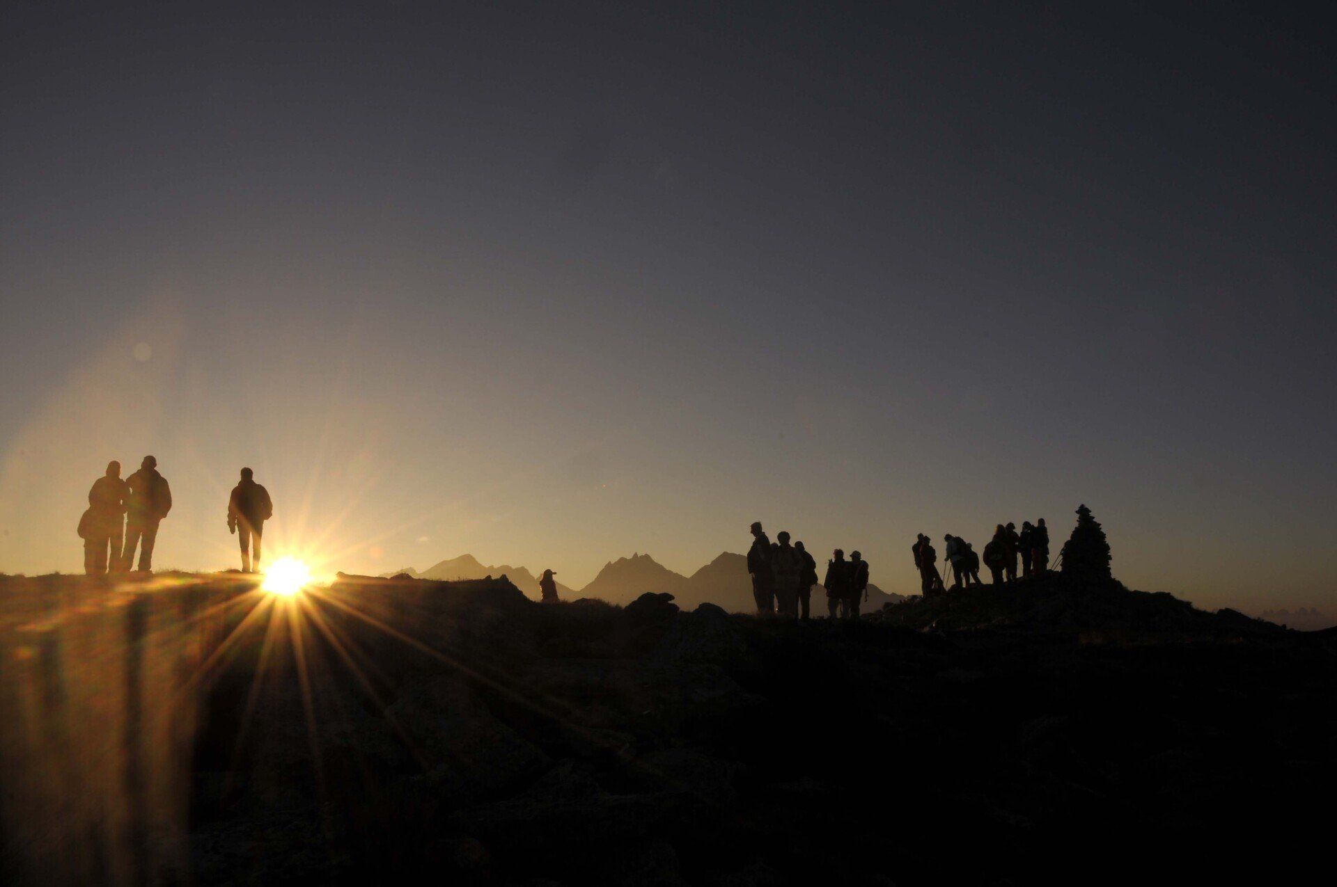 Eine Gruppe von Menschen steht bei Sonnenuntergang auf einem Hügel.