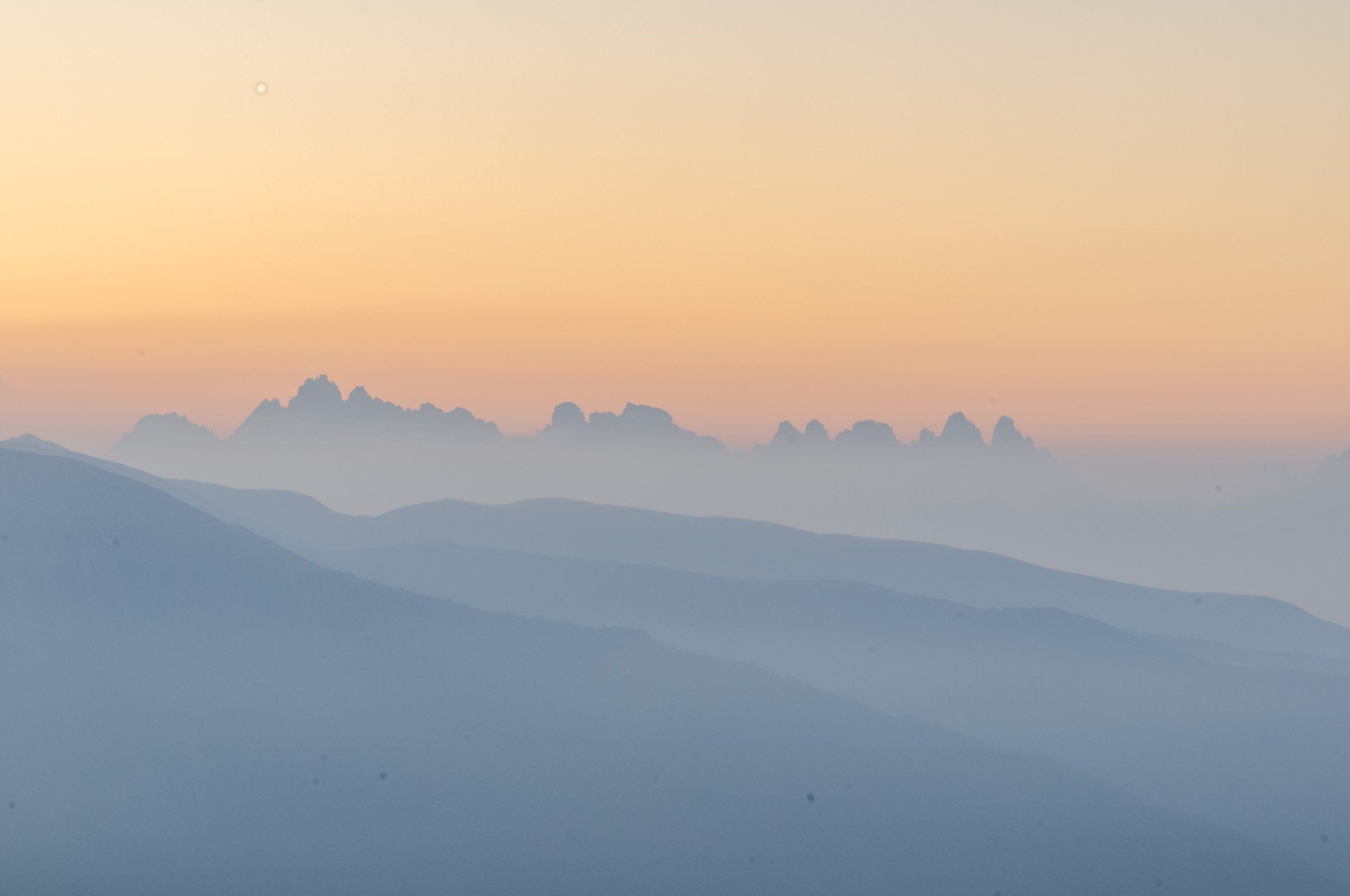 Bei Sonnenuntergang sind die Berge in Nebel gehüllt und der Himmel ist orange.