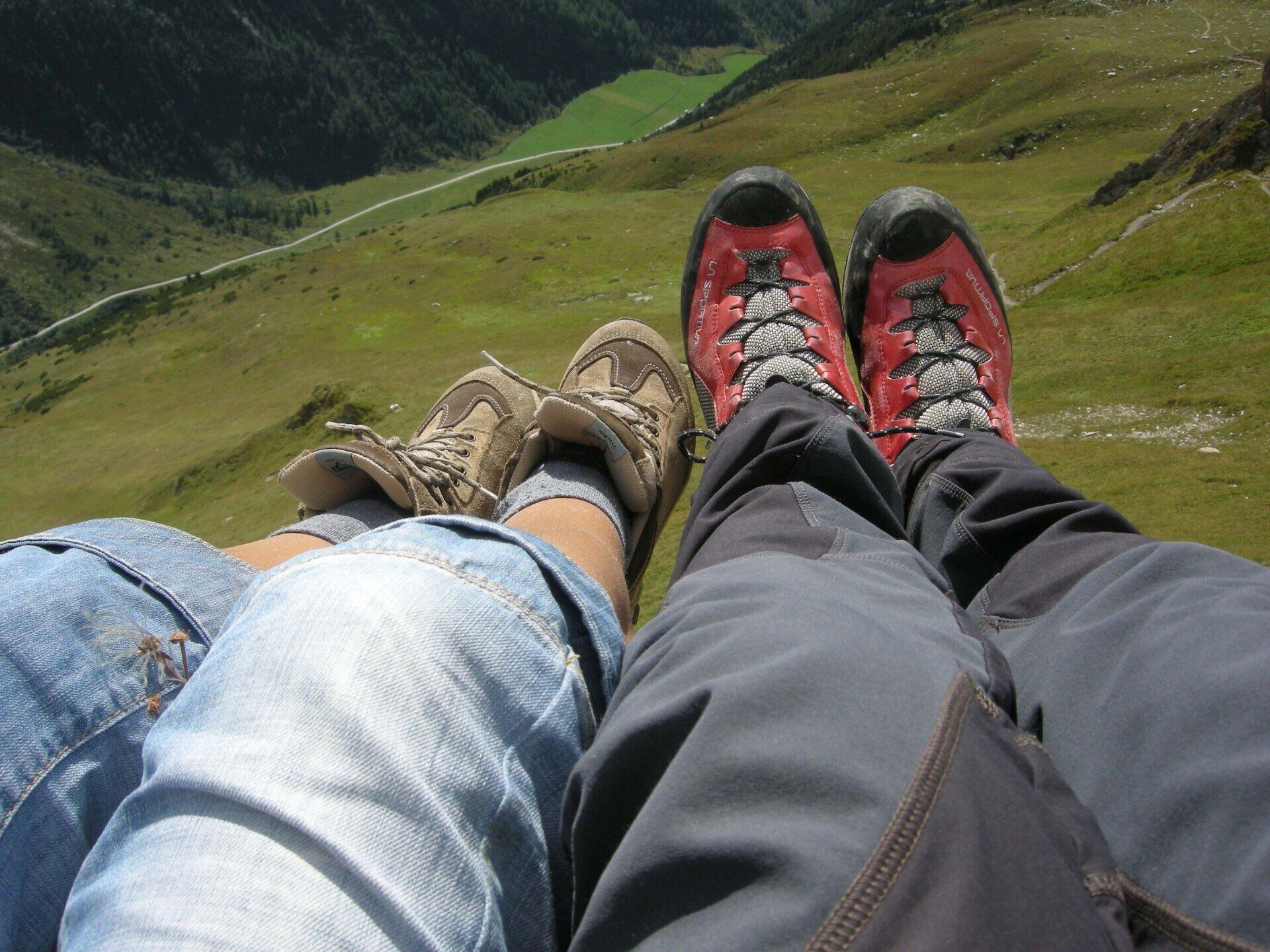 Eine Person, die mit hochgelegten Füßen auf einem Grashügel liegt
