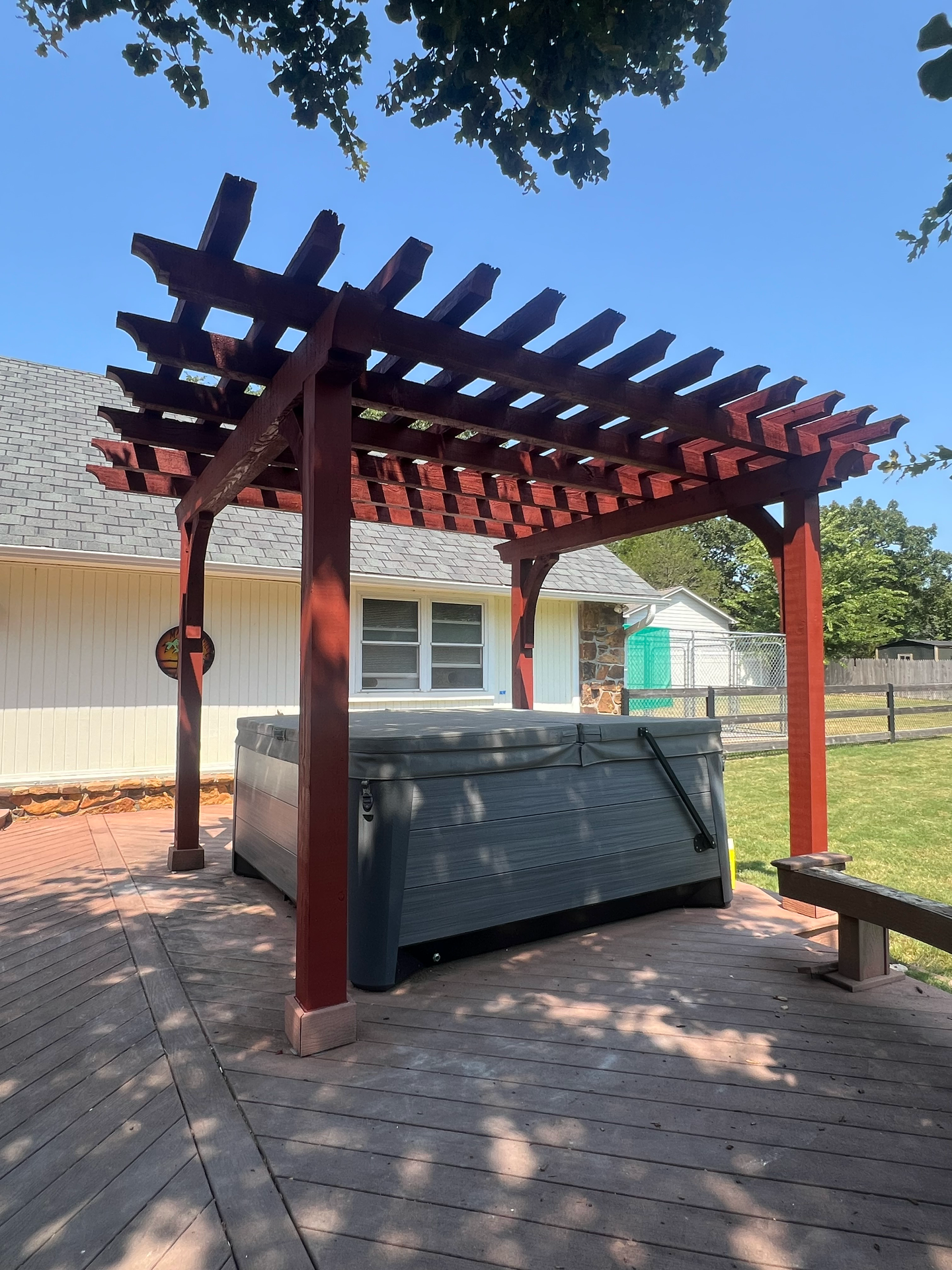 A hot tub under a pergola in front of a house
