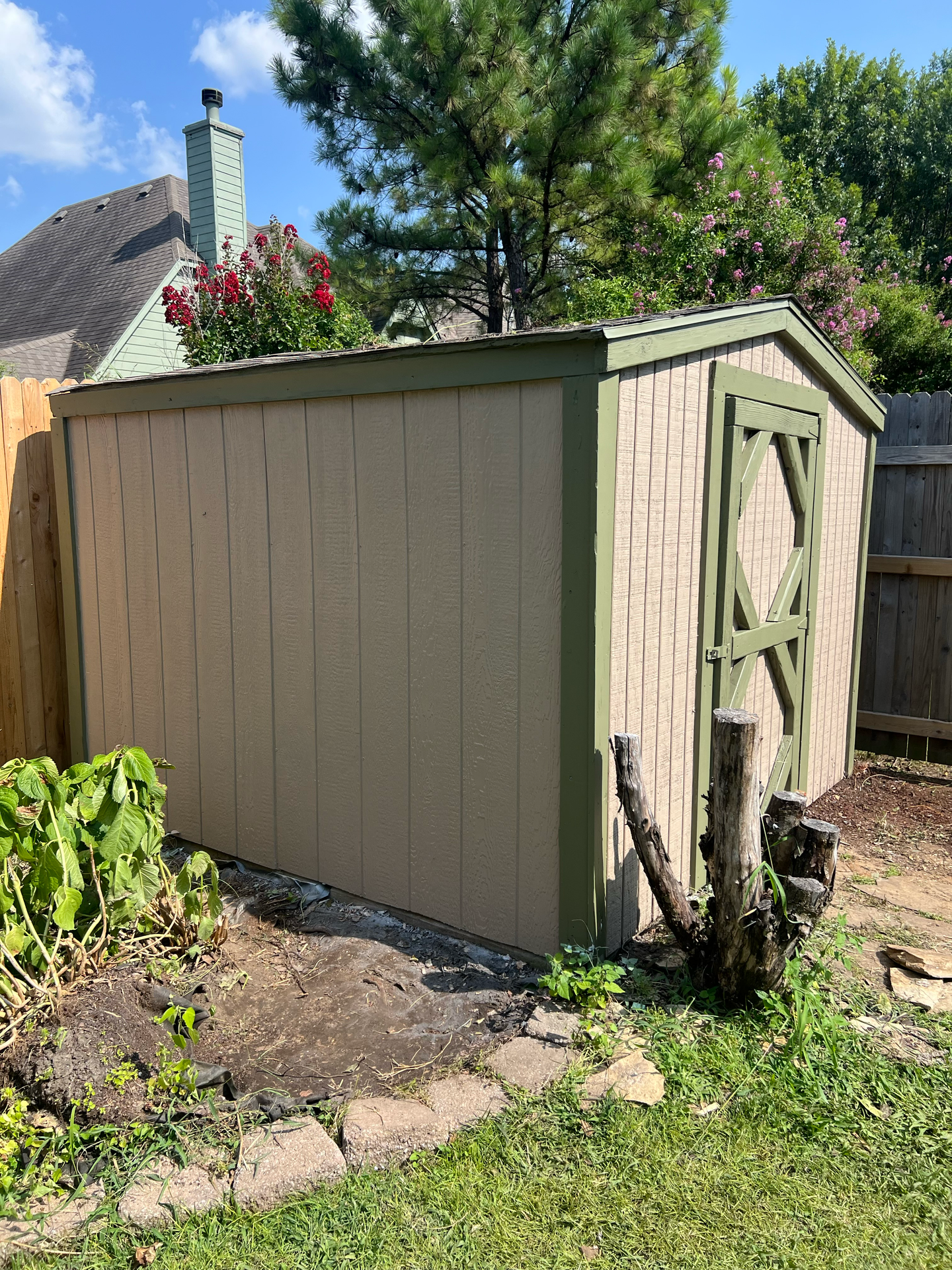 A shed is sitting in the middle of a yard next to a fence.