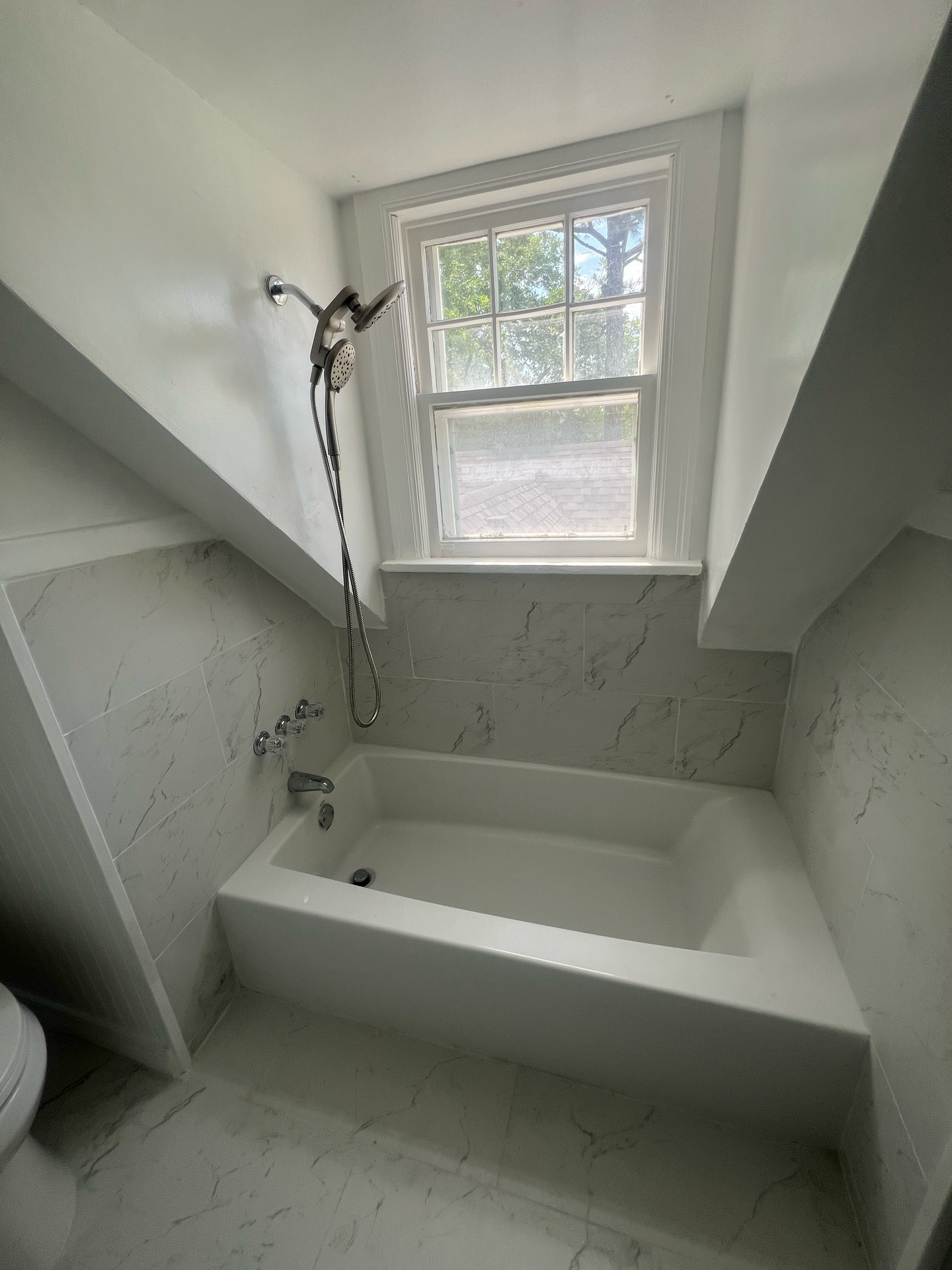 A bathroom with a bathtub and a window.