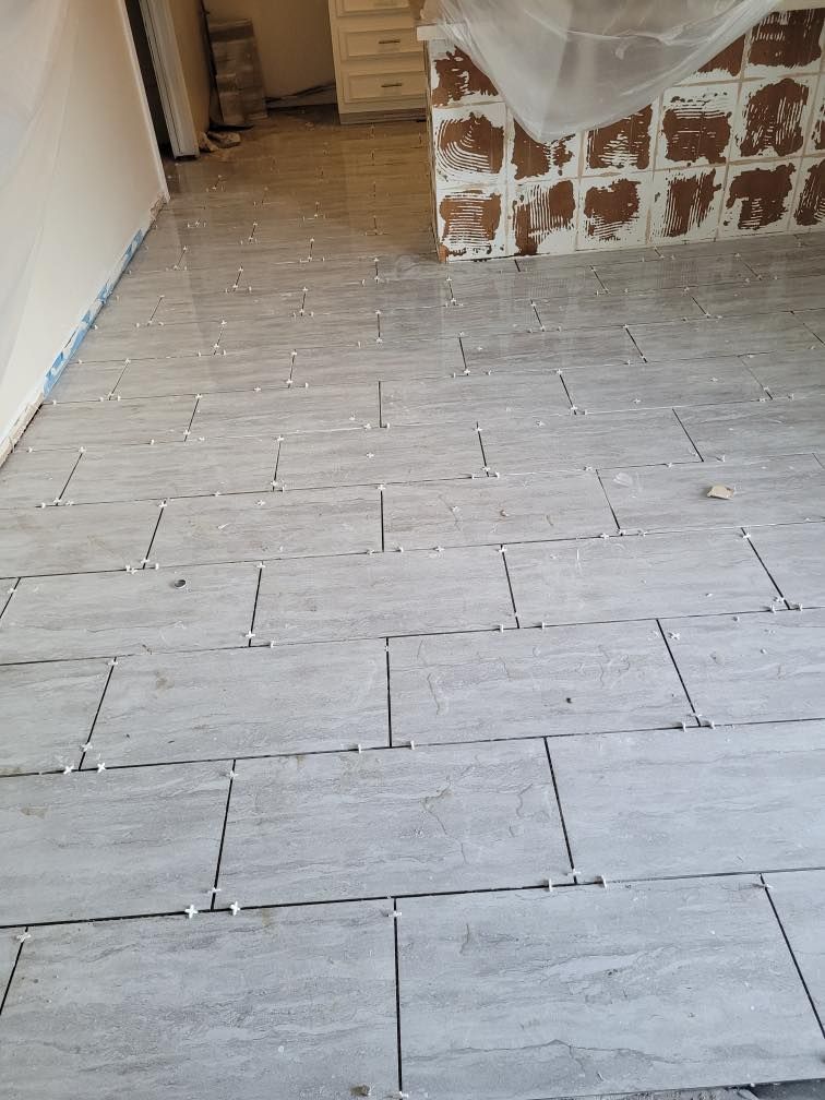 A tiled floor is being installed in a kitchen.
