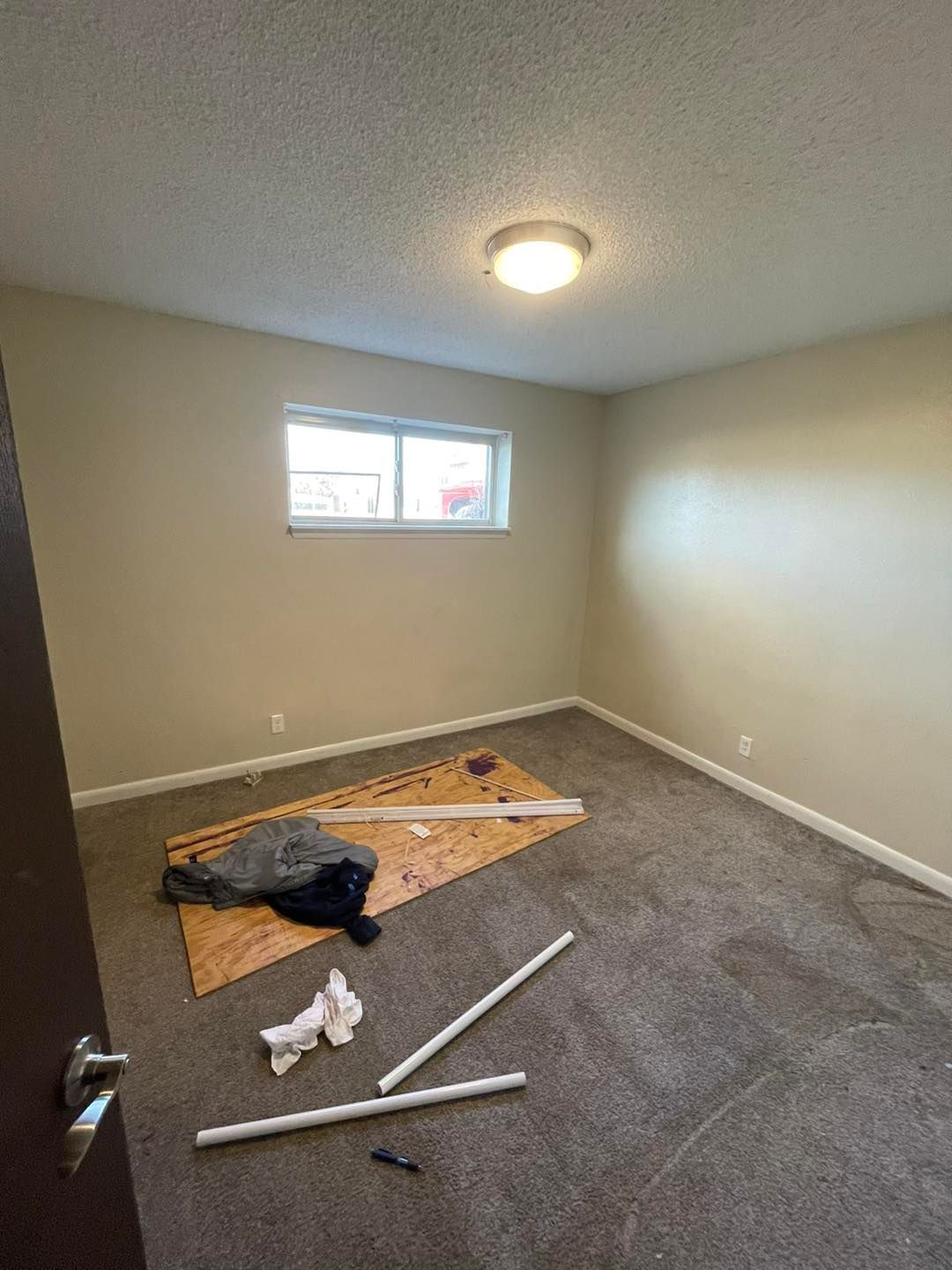 An empty room with a carpeted floor and a window.