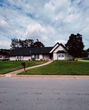 A white house with a black roof and a mailbox in front of it
