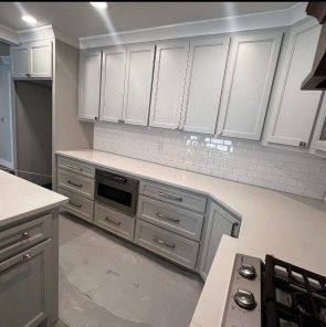 A kitchen with white cabinets , a stove , and a refrigerator.