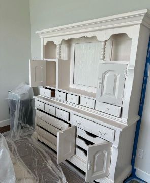 A white hutch with its doors open in a room.