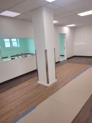 A large room with a wooden floor and a pillar in the middle of it.