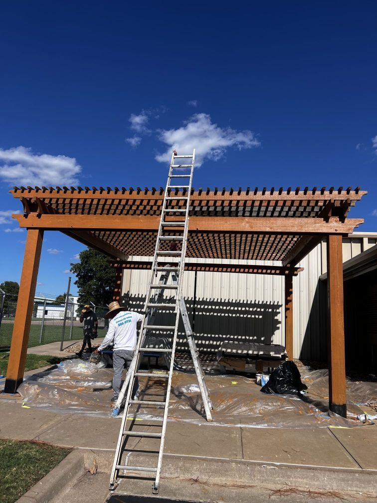 A man is standing on a ladder under a pergola.