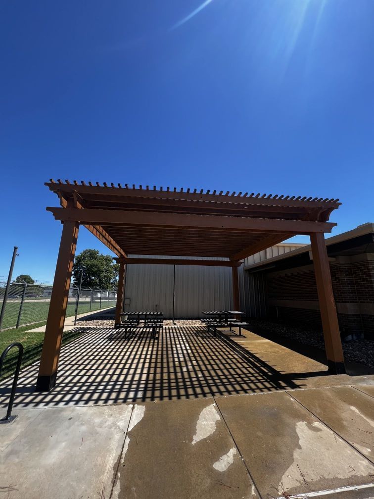 A wooden pergola with picnic tables underneath it