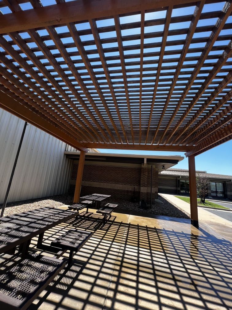 A wooden pergola with picnic tables underneath it
