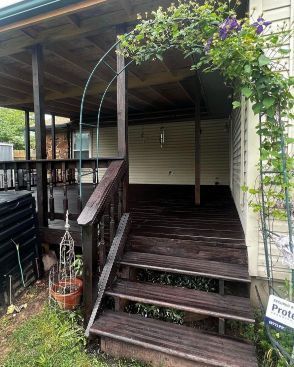 A wooden porch with stairs leading up to it next to a house.