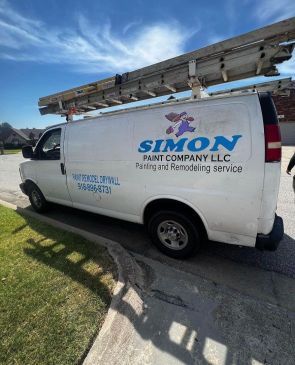 A white van with a ladder on top of it is parked on the side of the road.