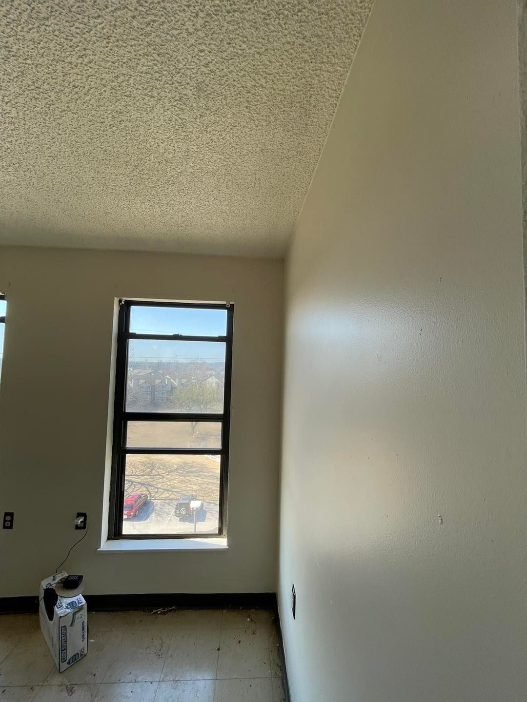 An empty room with a window and a heater in it.
