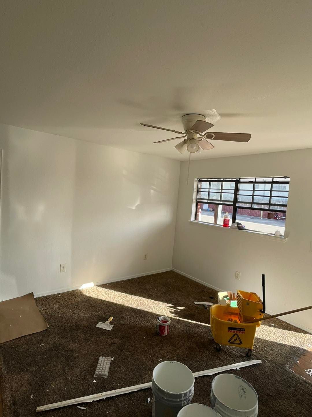 A living room with a ceiling fan and a window.
