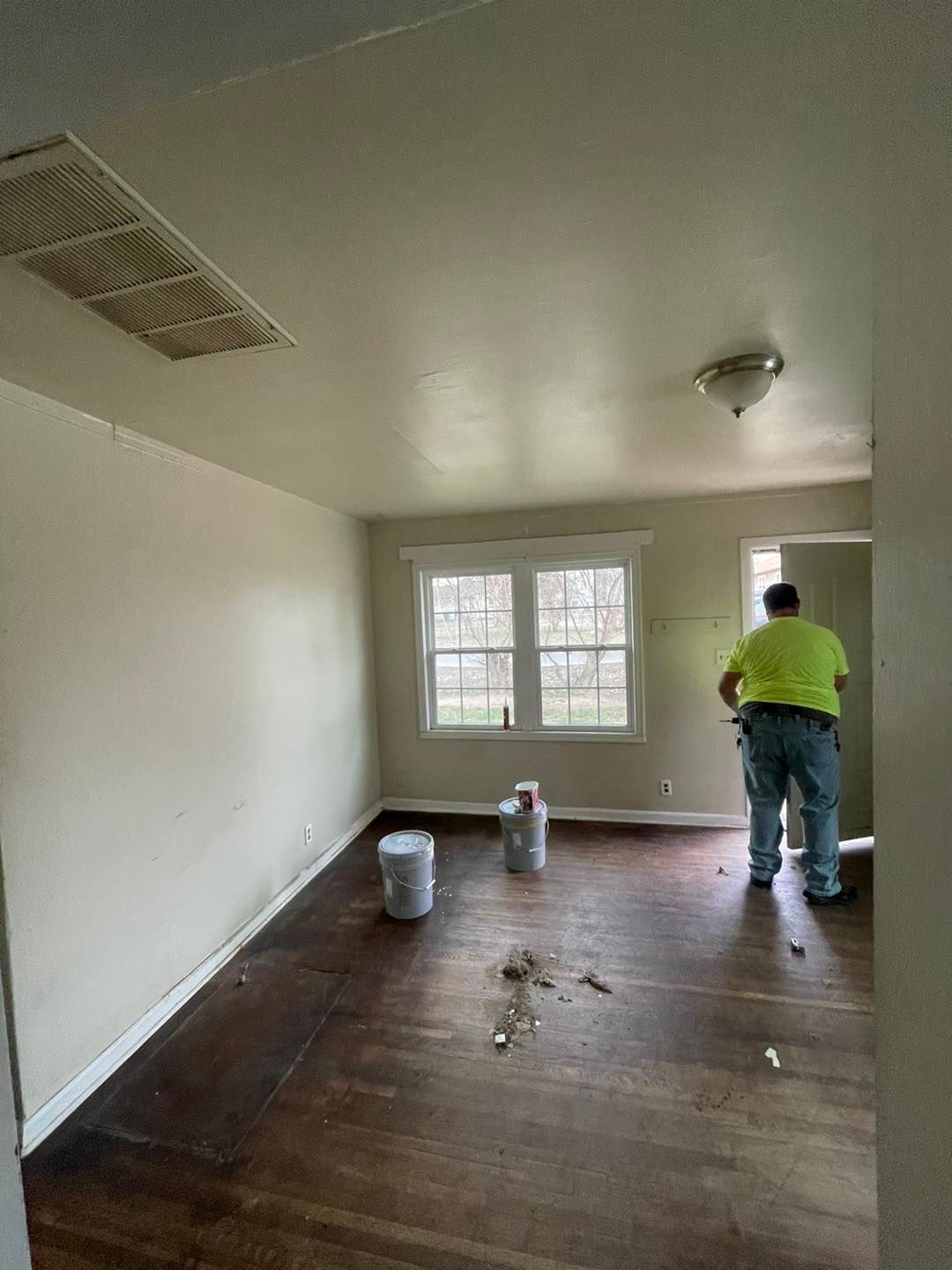 A man is standing in an empty room painting the walls.