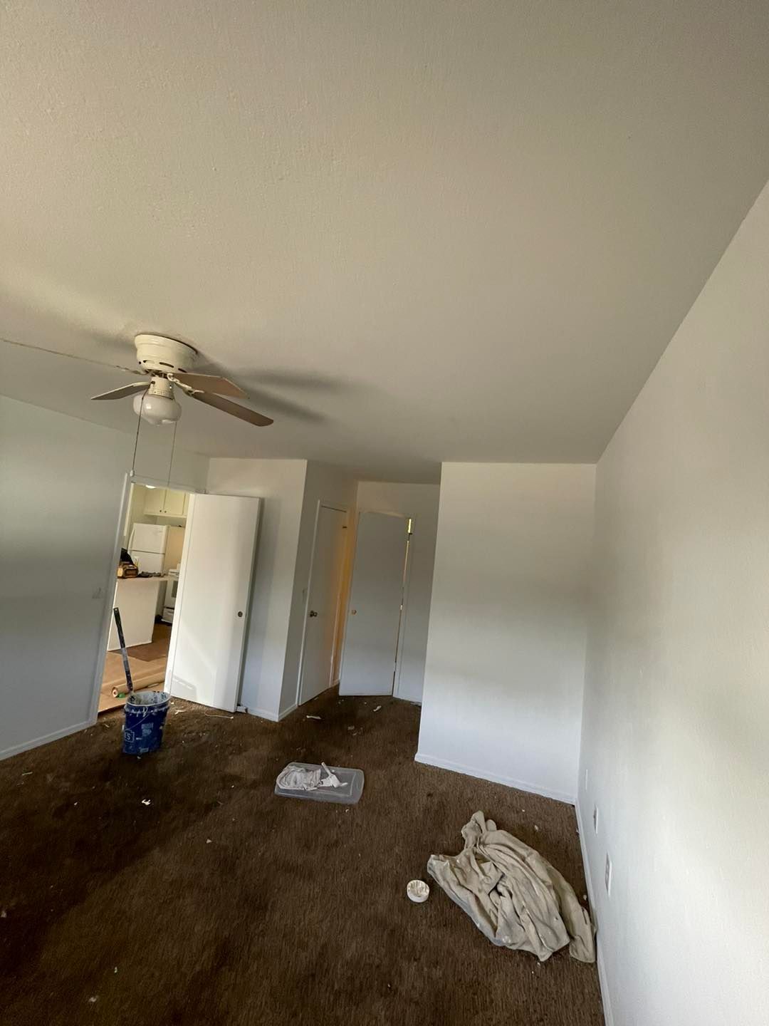 A living room with a ceiling fan and a blanket on the floor.