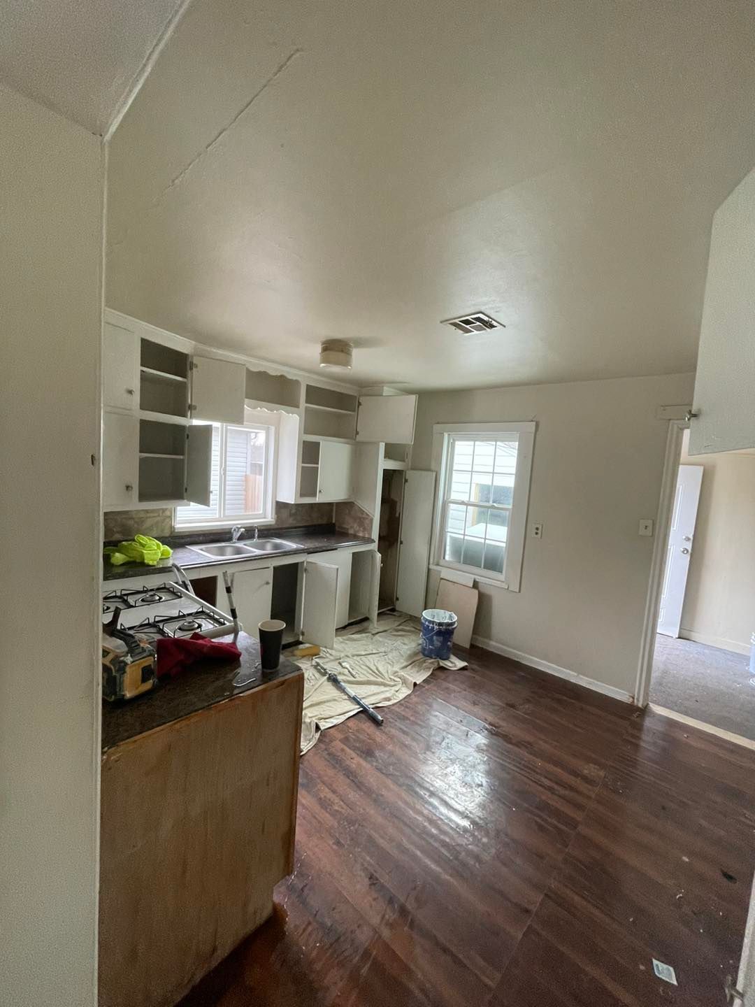 A kitchen with wooden floors and white cabinets is being remodeled.