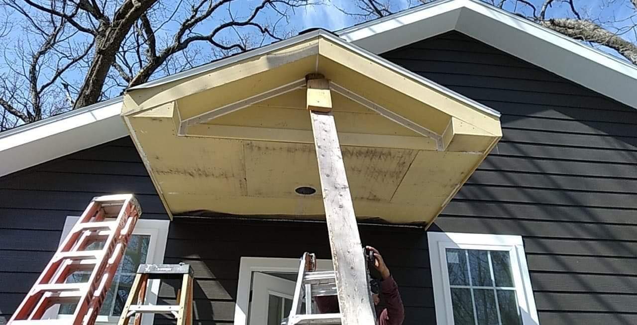 A man is standing on a porch next to a ladder.
