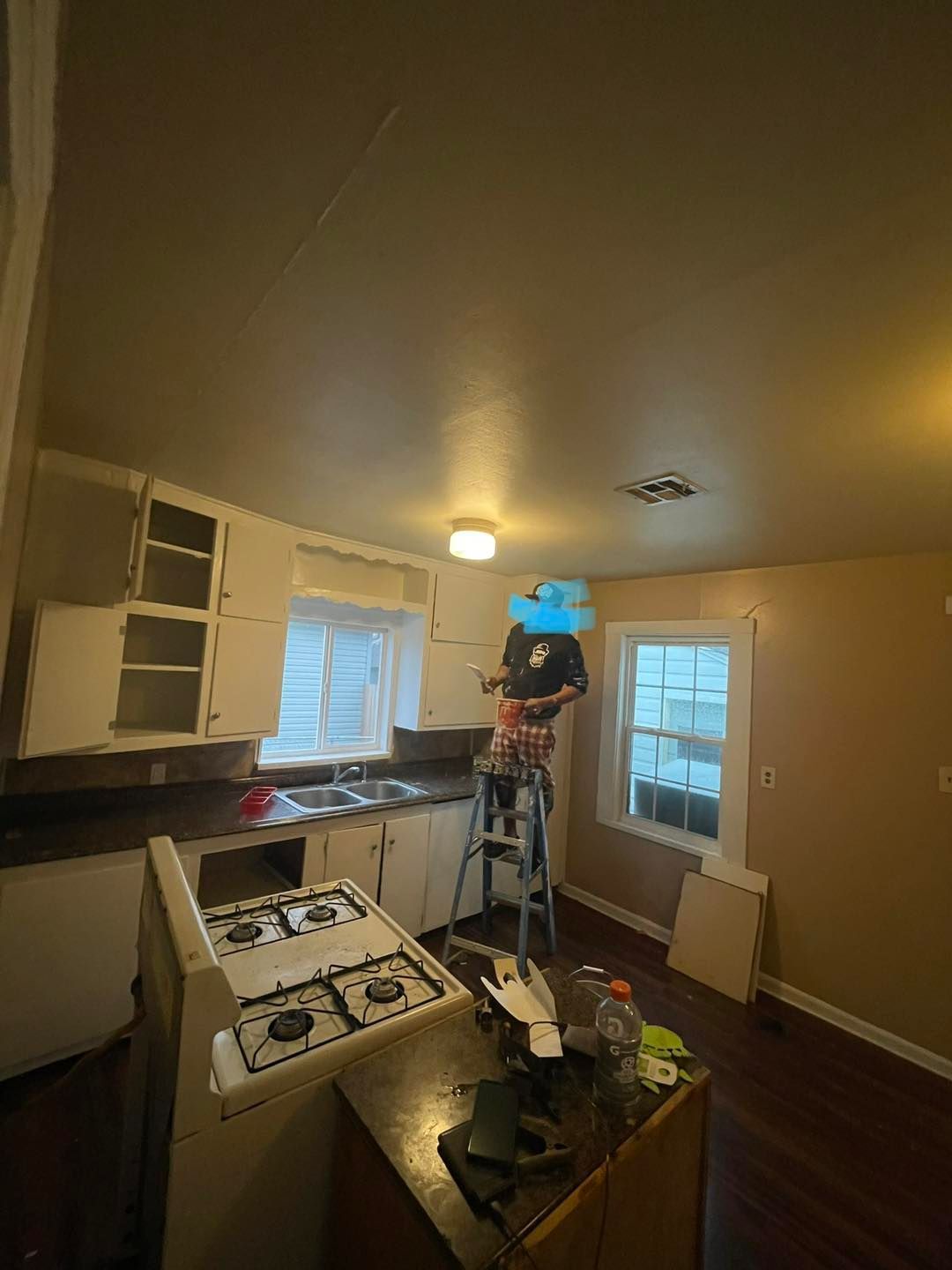 A man is standing on a ladder in a kitchen.