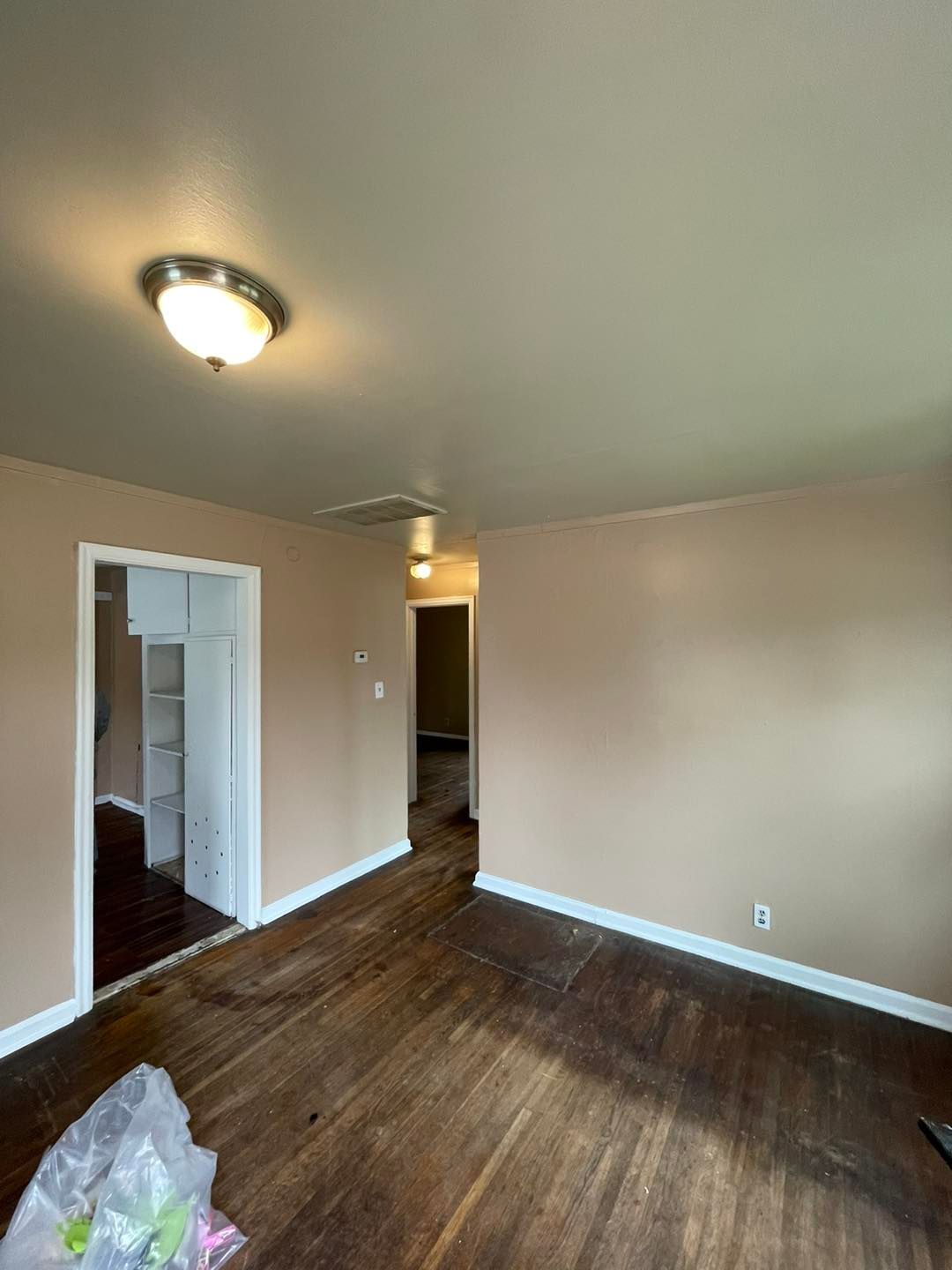 An empty living room with hardwood floors and a light on the ceiling.
