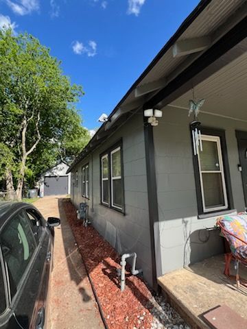 A car is parked in front of a house on a sunny day.