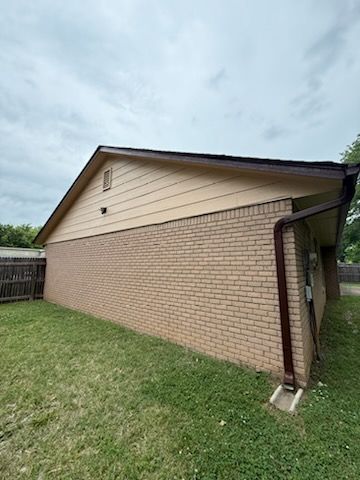 A brick house with a roof and a gutter in the backyard.
