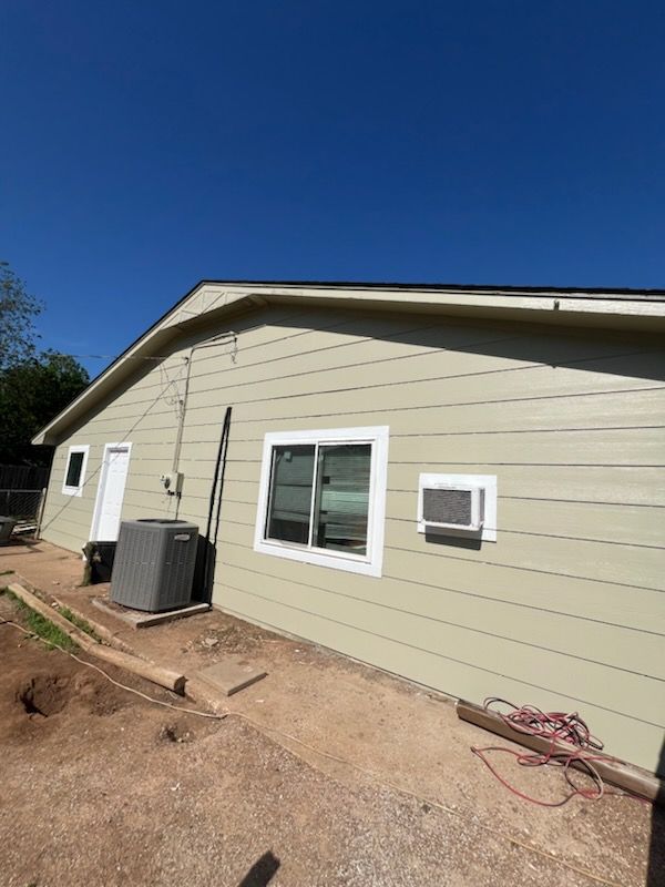 A house with a lot of windows and air conditioners on the side of it.