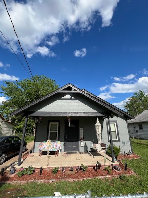 A small house with a porch and a car parked in front of it