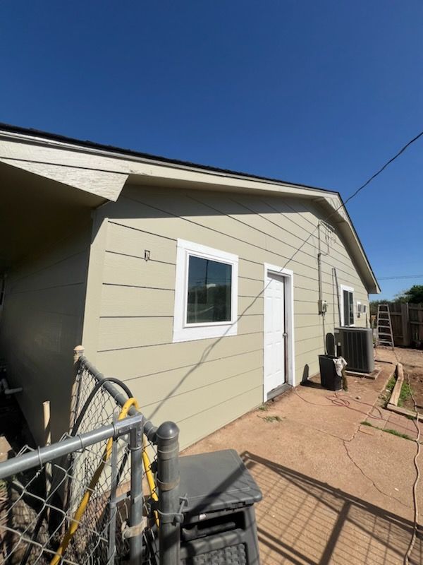 A house with a fence around it and a blue sky in the background.