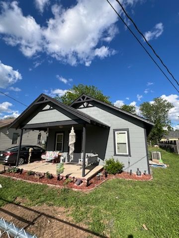 A small house with a porch and a car parked in front of it.
